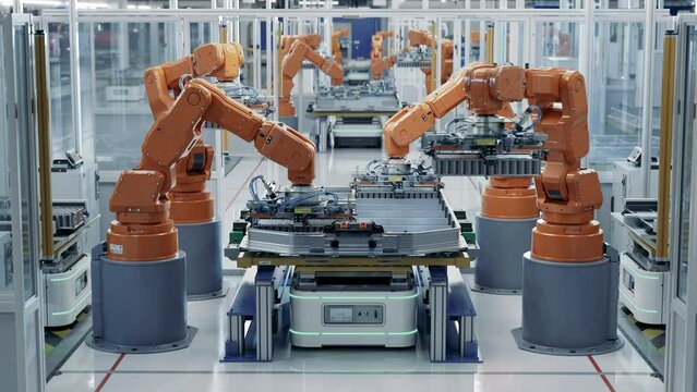 EV Battery Pack for Automotive Industry Assembled on Production Line with Orange Robotic Arms.  Automated Battery Manufacturing Line Equipped with Robot Arms. Electric Car Smart Factory