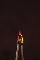 two lighted matches on a dark background