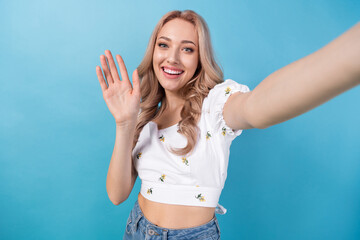 Photo of charming excited woman dressed white top waving arm hi recording video vlog isolated blue color background © deagreez