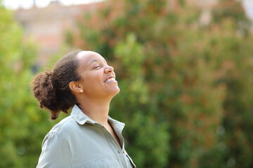 Happy black woman breathing fresh air in a garden