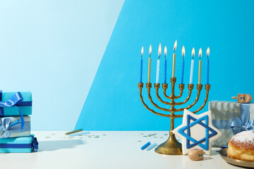Hanukkiah, gingerbread, gift boxes and donut on blue background, space for text