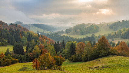 Autumn foggy landscape of hills with colorful trees. The Orava region of Slovakia, Europe.