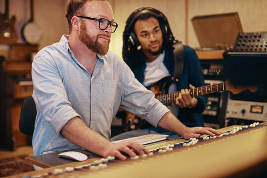 Music producer working with a musician in his recording studio