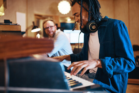 Smiling young musician playing keyboards during a recording studio session