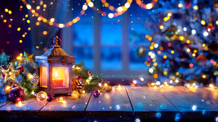 Lantern And Christmas Tree Glowing On Table With Decoration And String Lights - Bokeh And...