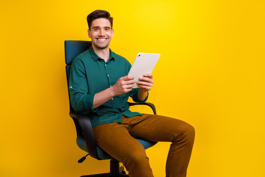 Photo Of Attractive Stylish Man Sitting Armchair Holding Modern Gadget Ipad Reading Resume News Isolated On Yellow Color Background