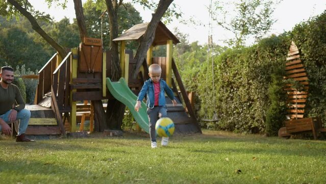 A little 3-year-old boy is kicking a soccer ball