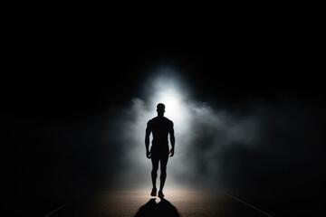 Silhouette of a basketball player walking against the background of smoke and sports spotlights. - obrazy, fototapety, plakaty