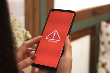 woman using smartphone with warning triangle showing a system error. Concepts of system...