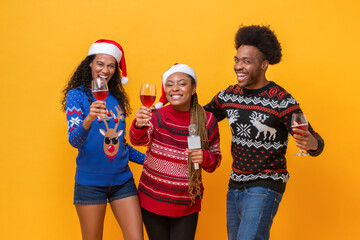 Happy diverse friends in Christmas sweaters drinking, singing, celebrating and having fun together...