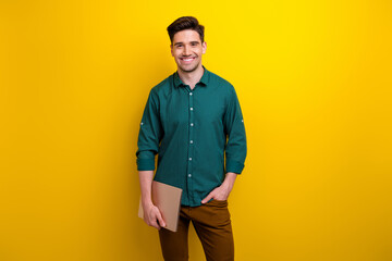 Photo of cheerful nice confident man wear stylish clothes hold netbook isolated on yellow color...