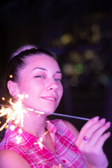 A young woman with a sparkler at the party by the neon lights