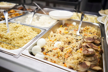 A traditional Uzbek dish called pilaf. Rice with meat, carrots, onions, quail eggs and kazy . Glass Showcase in a buffet or self-service restaurant.