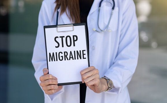 Stop Migraine text on a notebook on a table next to it is a stethoscope and tablets, medical concept