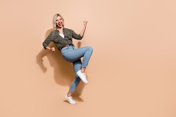Fototapeta na wymiar Full length photo of astonished lady succeeded work raise leg yell hooray wear trendy clothes isolated beige color background