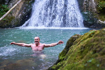 Strong man bathing in a waterfall