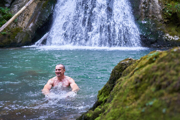 Strong man bathing in a waterfall