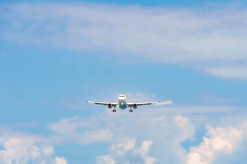 Close-up of a passenger plane with its headlights on is landing against a background of blue sky...