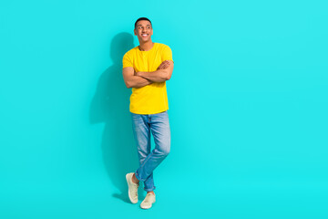 Fototapeta na wymiar Full length photo of cheerful nice young man crossed arms look interested empty space isolated on teal color background