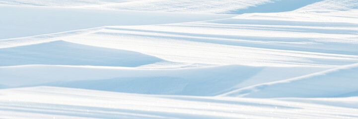 Snow texture. Wind sculpted patterns on snow surface. Wind in the tundra and in the mountains on the surface of the snow sculpts patterns and ridges (sastrugi). Arctic, Polar region. Winter background