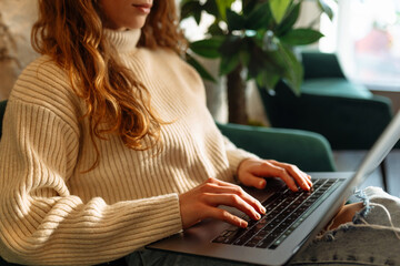 Woman works on a laptop in a cafe. Close-up of hands working on a laptop keyboard.  Freelance,...