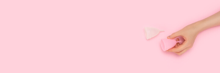 Banner with hand hold menstrual cup on a pink background.