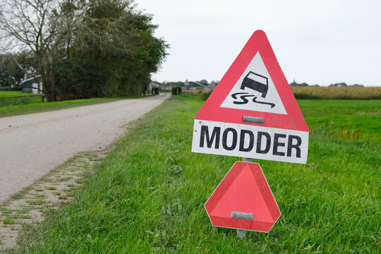 Warning sign for mud or modder in dutch on the road in an agricultural environment. Mud gets on the road by farmers during harvest.