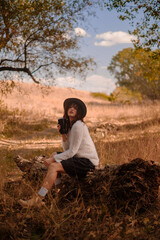 young woman relaxing outdoors on an autumn day, traveling to the forest, sitting on a wooden log in the forest and drinking hot tea, unity with nature, searching for the meaning of life