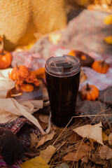 Thermos with cups of coffee and croissants on plaid in autumn park