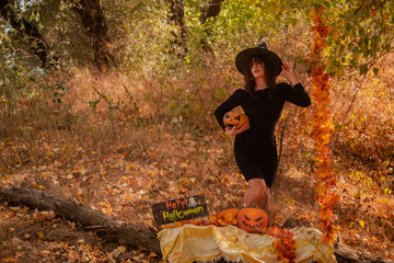 Beautiful woman in witch costume with Jack-o'-lantern in forest, Halloween party, smiling evil...