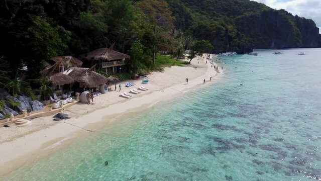 Tropical beachfront Thatch bungalows of Vellago resort on Seven Commandos Beach in El Nido. Aerial