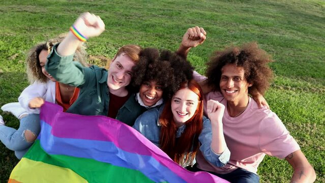 Excited young friends of LGBT community celebrating gay pride day festival. Group of diverse joyful cheerful people having fun together under shower of confetti. Generation z and social event.