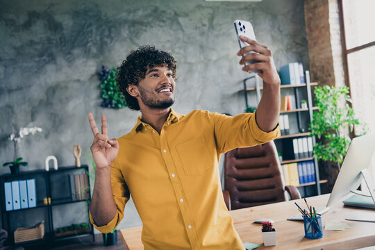 Photo of cheerful good mood guy office manager speaking talking online showing v-sign room indoors - Powered by Adobe