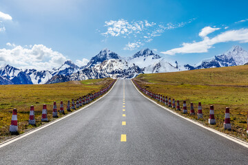Fototapeta na wymiar Straight highway road and snow mountain nature landscape under blue sky