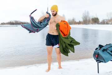 Winter swimming change robe. A man changes clothes after swimming in the cold winter lake.