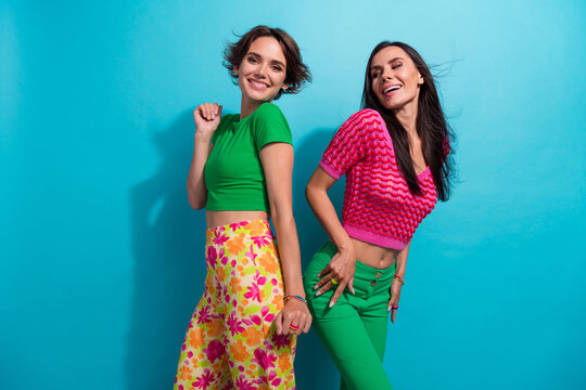 Photo of pretty shiny girls dressed colorful outfits dancing having fun empty space isolated blue color background