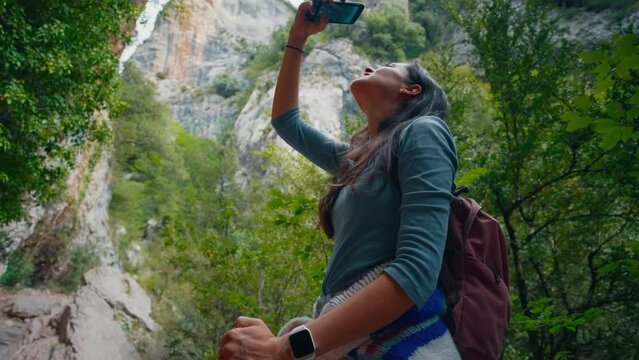 Hiking female tourist taking pictures on her smartphone at vacation travel