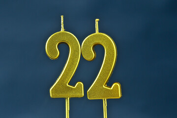 close up on the gold number twenty-second candle on a dark background.
