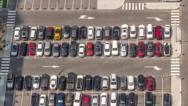 Aerial view of many colorful cars parked on parking lot with lines and markings for places and directions during all day timelapse with long shadows moving fast. Dubai financial district avenue