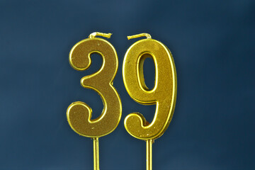 close up on the gold number thirty-ninth candle on a dark background.
