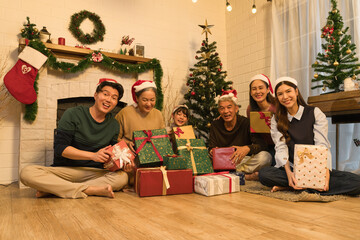 Obraz na płótnie Canvas Happy Asian family with with multi generations celebrating christmas with gifts in living room with Christmas tree