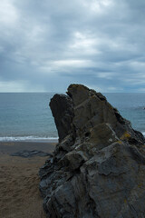 Nature s Sculpture: A Rocky Outcrop on a Sandy Shore Under a Cloudy Sky