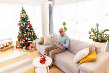 Senior man reading newspapers and drinking coffee on Christmas morning