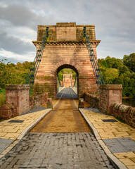 Obraz premium Portrait of entrance to Union Chain Bridge, a suspension road bridge that spans the River Tweed between England and Scotland located four miles upstream of Berwick Upon Tweed