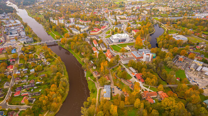 City of Valmiera from above in autumn. Panoramic Fall Landscape with Cityscape, Clouds, and Foliage. Cityscape with autumn foliage, flowers, and a tree in high angle view.