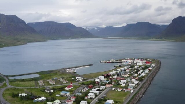 Aerial backwards shot Flateyri town at Westfjord with mountain range in background, Iceland