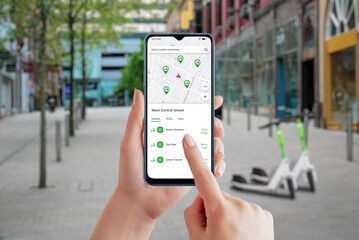 Electric scooter sharing platform app on smartphone. City street and scooters in background