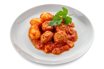 Meatballs and potatoes cooked with tomato sauce with parsley leaves on white plate isolated