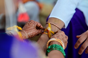 Hands of bride wearing turmeric thread on hand of groom in indian wedding ceremony. Hindu wedding rituals. Hands of bride and groom. Wedding worship. Maharashtra culture. Marathi wedding