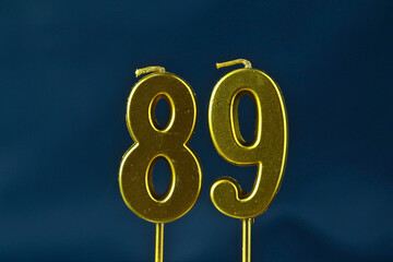 close up on gold number eighty-ninth candle on a dark background.
